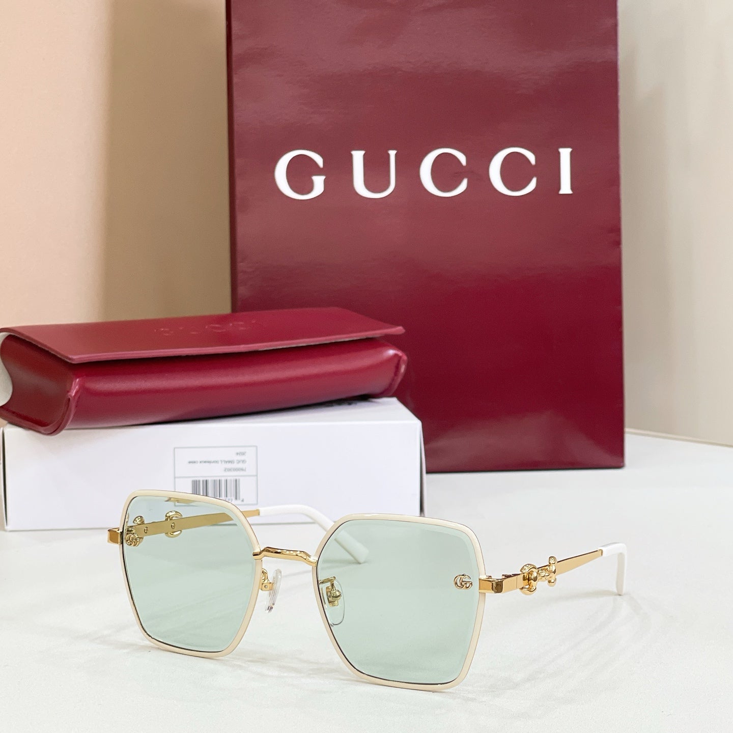 Gucci square sunglasses with gold frame, light blue lenses, and gold-tone chain temples.