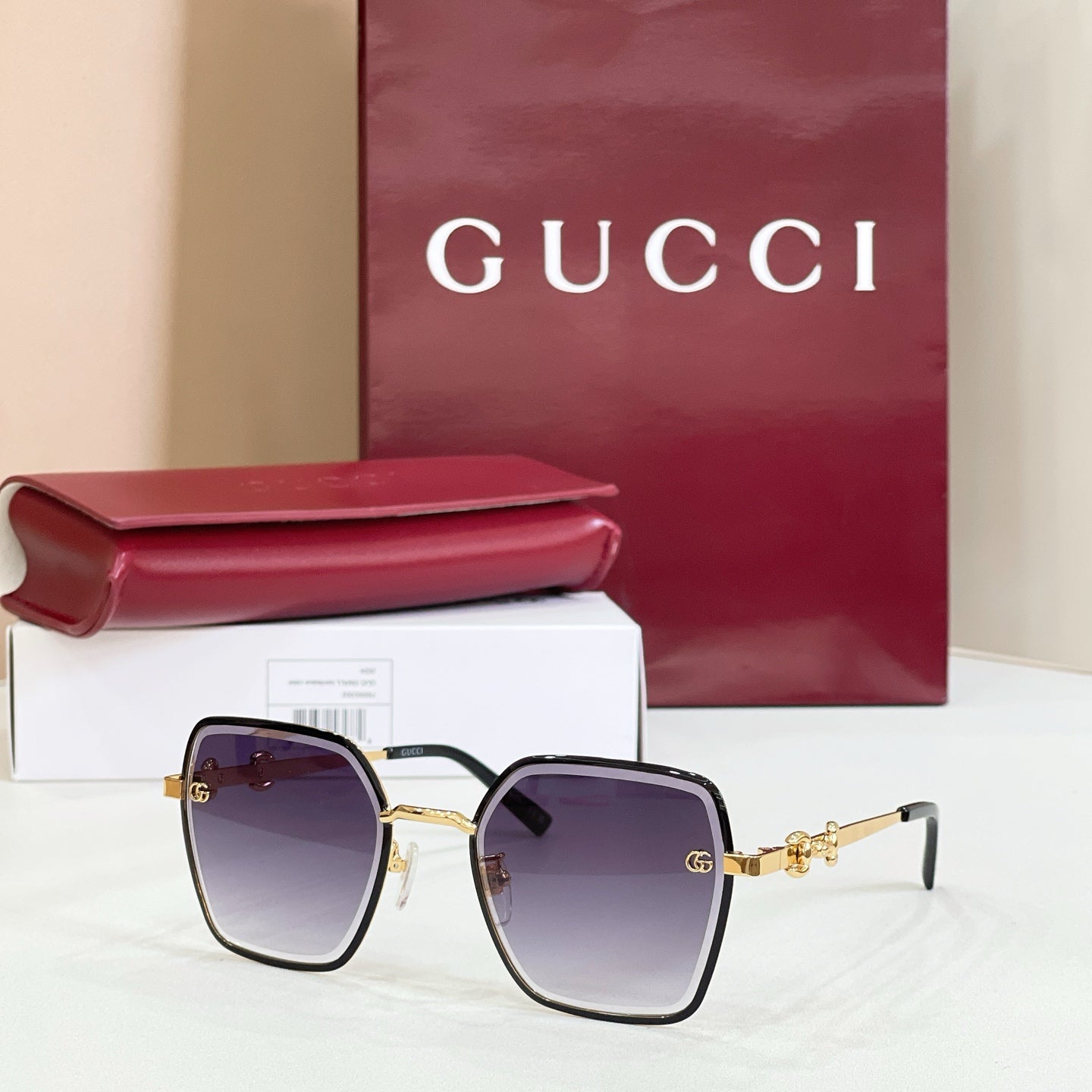 Gucci square sunglasses with dark lenses, black frame, and gold-tone chain temples.