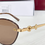 Gucci round sunglasses close-up: gold arms, brown lenses, logo charm at hinge
