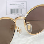 Gucci round sunglasses close-up: gold frame, brown lenses, logo detail at bridge