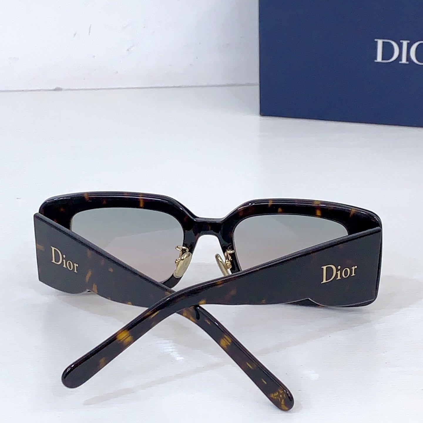 Dior sunglasses with dark tortoiseshell frame and light lenses, folded at the arms