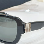 Black sunglasses close-up with gold-tone hinge and glossy frame edges