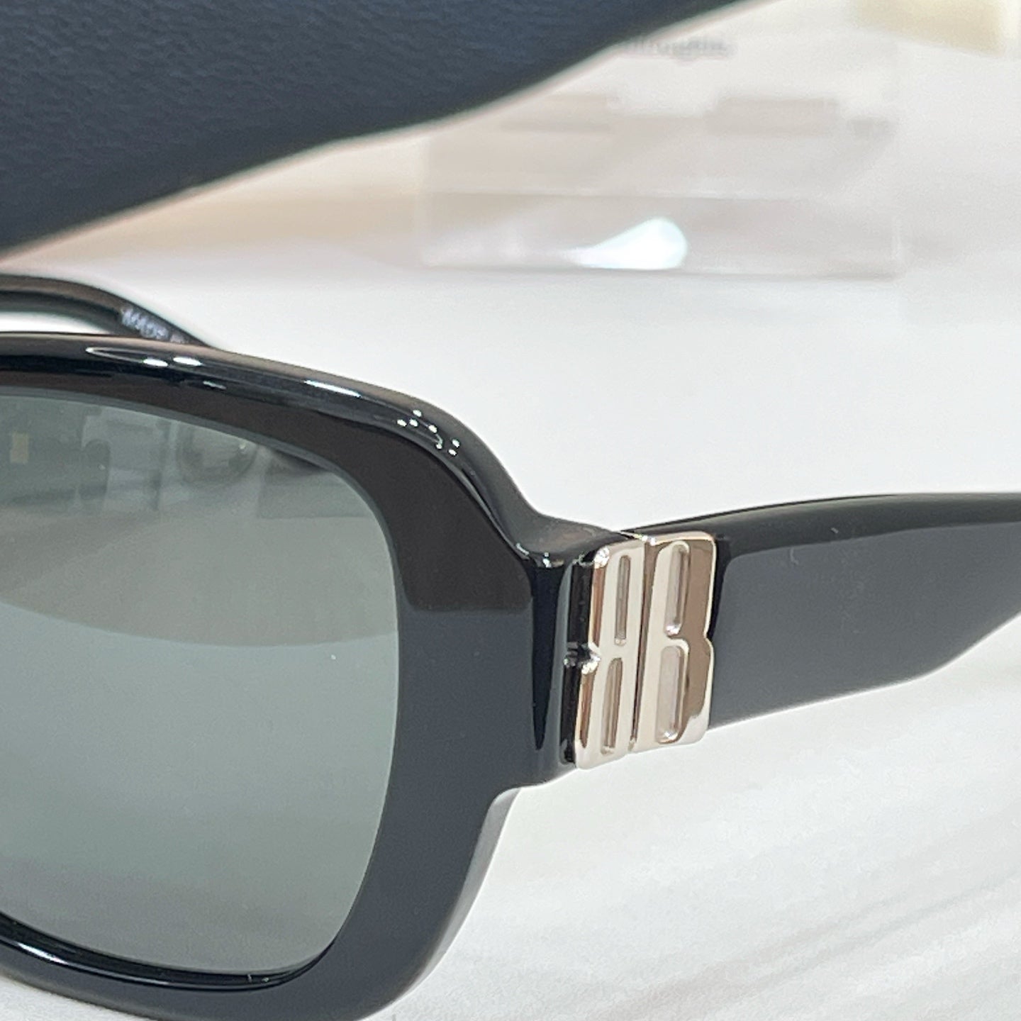 Black sunglasses close-up with gold-tone hinge and glossy frame edges