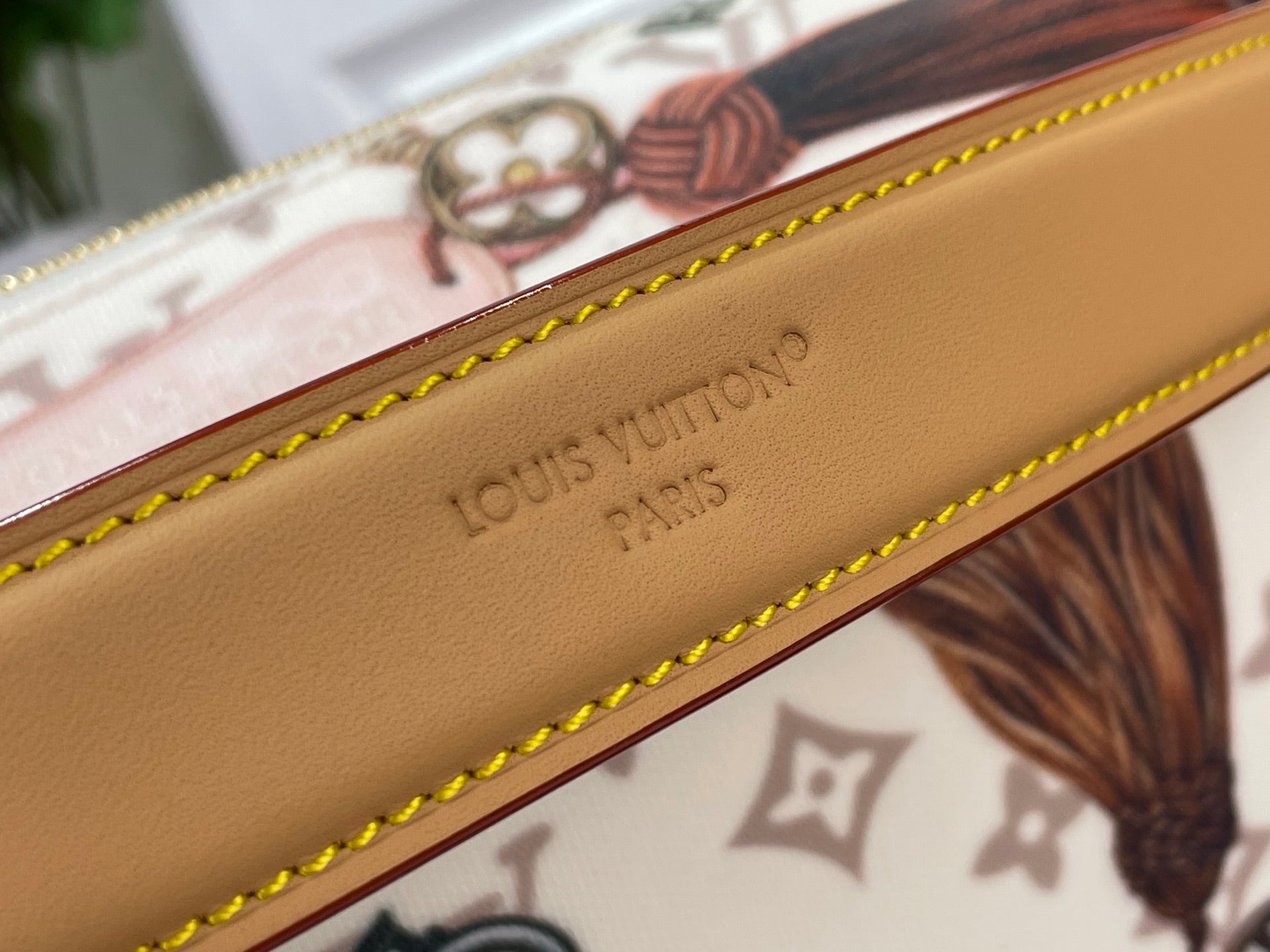 Tan leather strap embossed with Louis Vuitton Paris text and yellow edge stitching