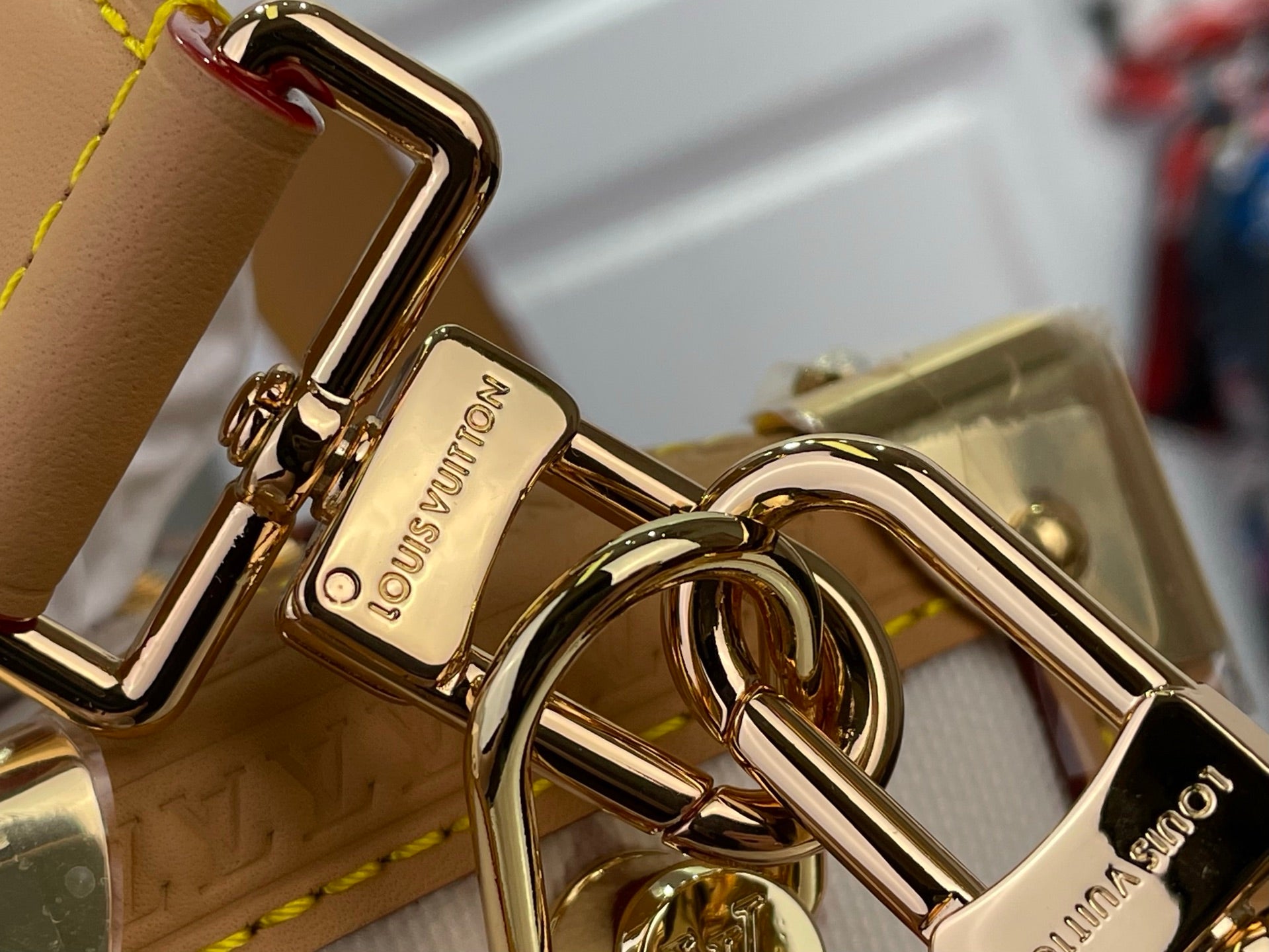 Gold-tone keyhole hardware with Louis Vuitton engraving on tan leather strap and D-ring