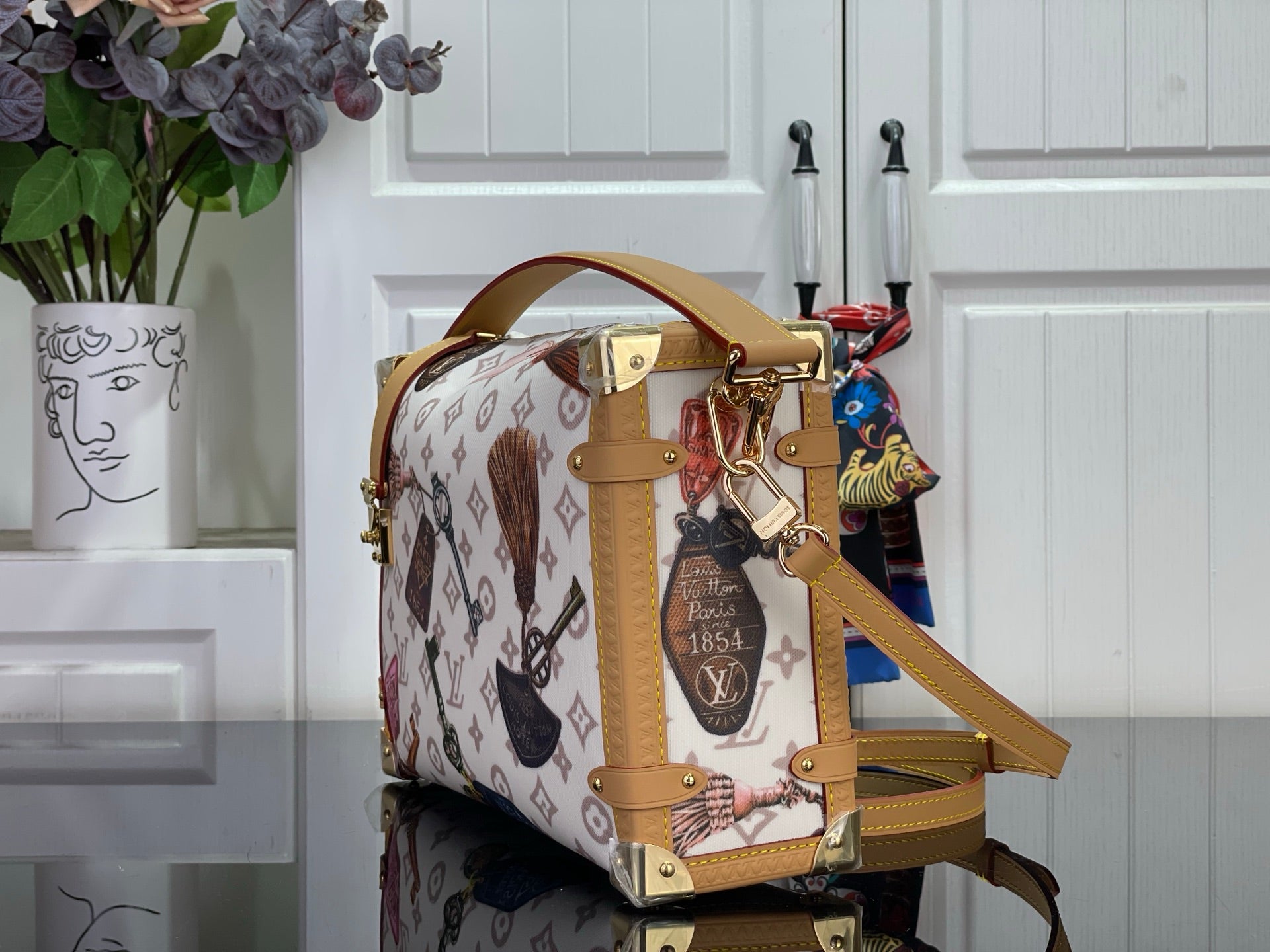 Monogram handbag with tan leather panels, top handle, gold-tone hardware, and shoulder strap