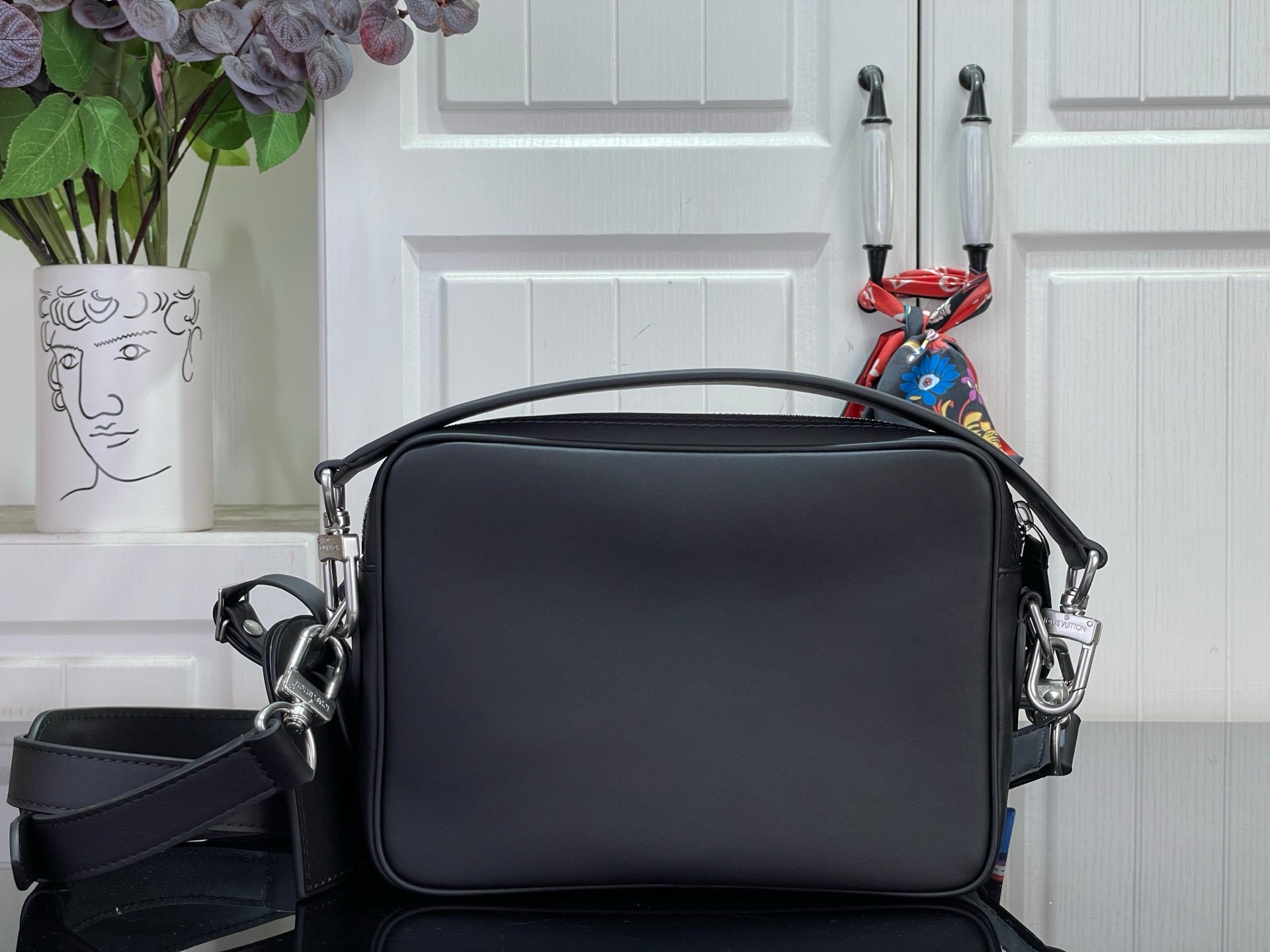 Louis Vuitton crossbody bag with curved front flap, silver hardware, and zipper