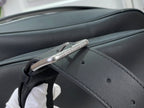 Dark leather shoulder strap with metal buckle and punched adjustment holes.