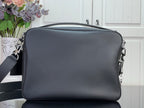 Dark leather crossbody bag with top zip and side metal hardware rings.