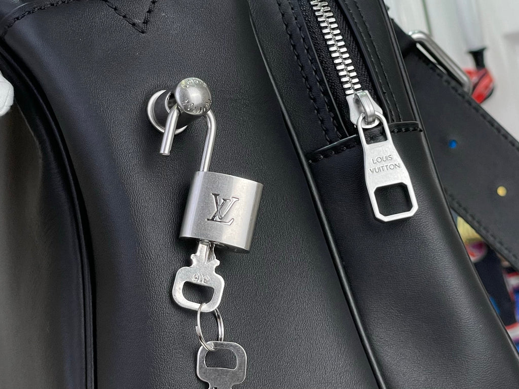 Louis Vuitton bag lock charm and metal zipper pull on dark leather
