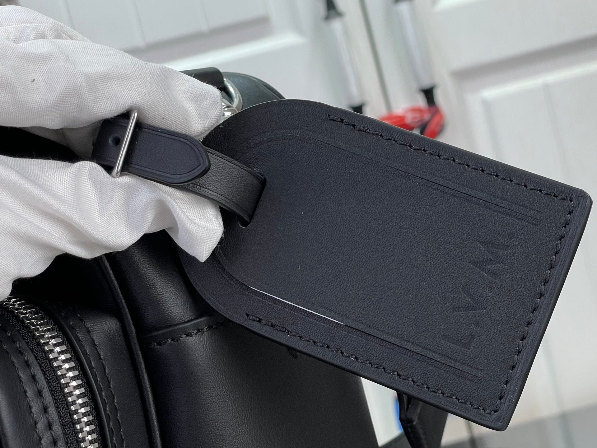 Dark leather bag pocket with strap and embossed LV pattern on front.