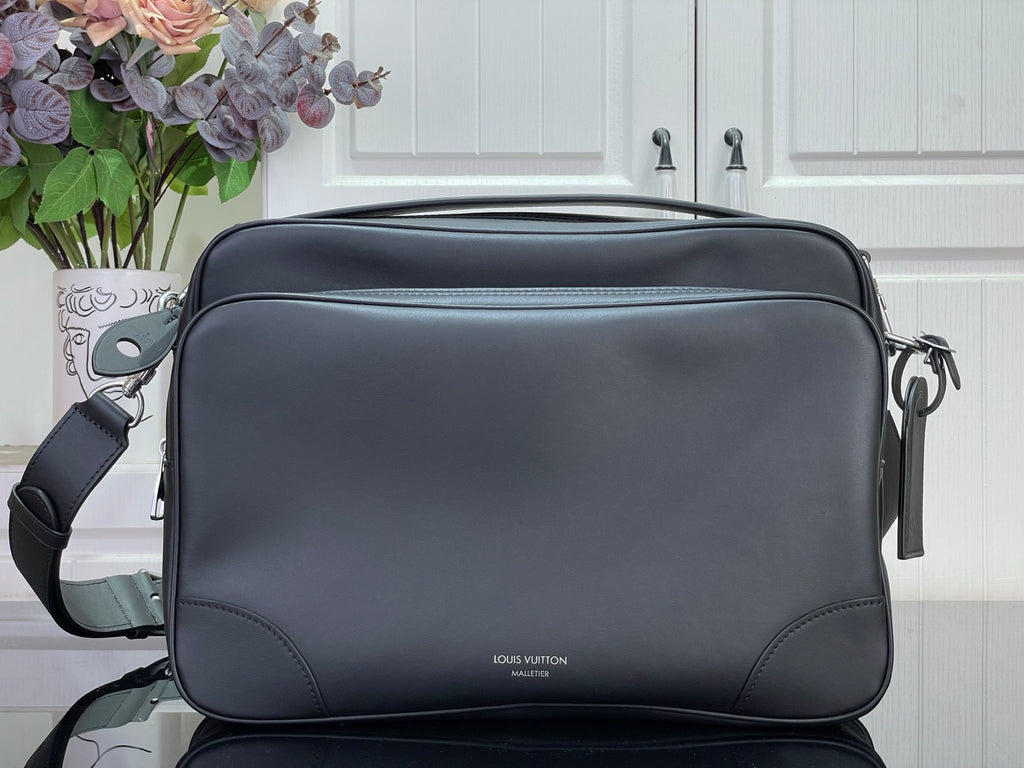 Dark leather crossbody bag with flap, top zip, and adjustable shoulder strap.