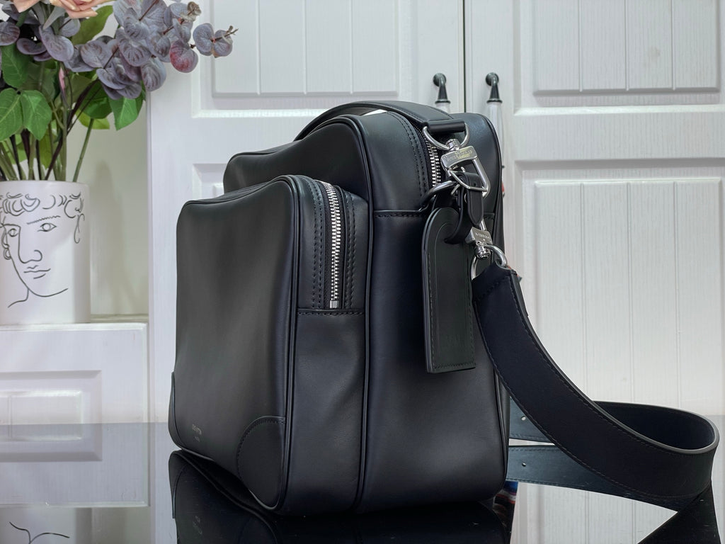 Dark leather crossbody bag side profile with zipper pulls and adjustable strap.