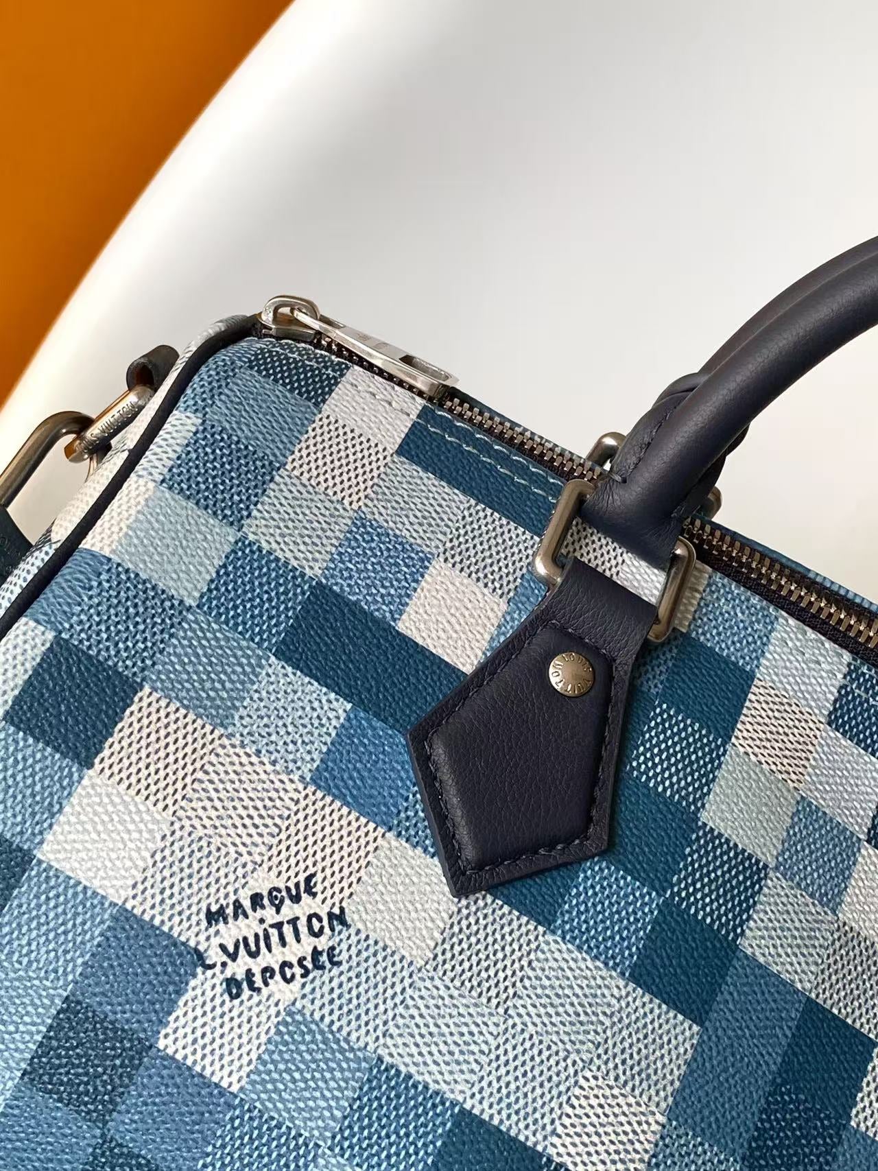 Blue checkered fabric handbag with black leather trim and stitched logo patch