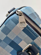 Blue checkered handbag corner with gold-tone zipper pull and leather strap