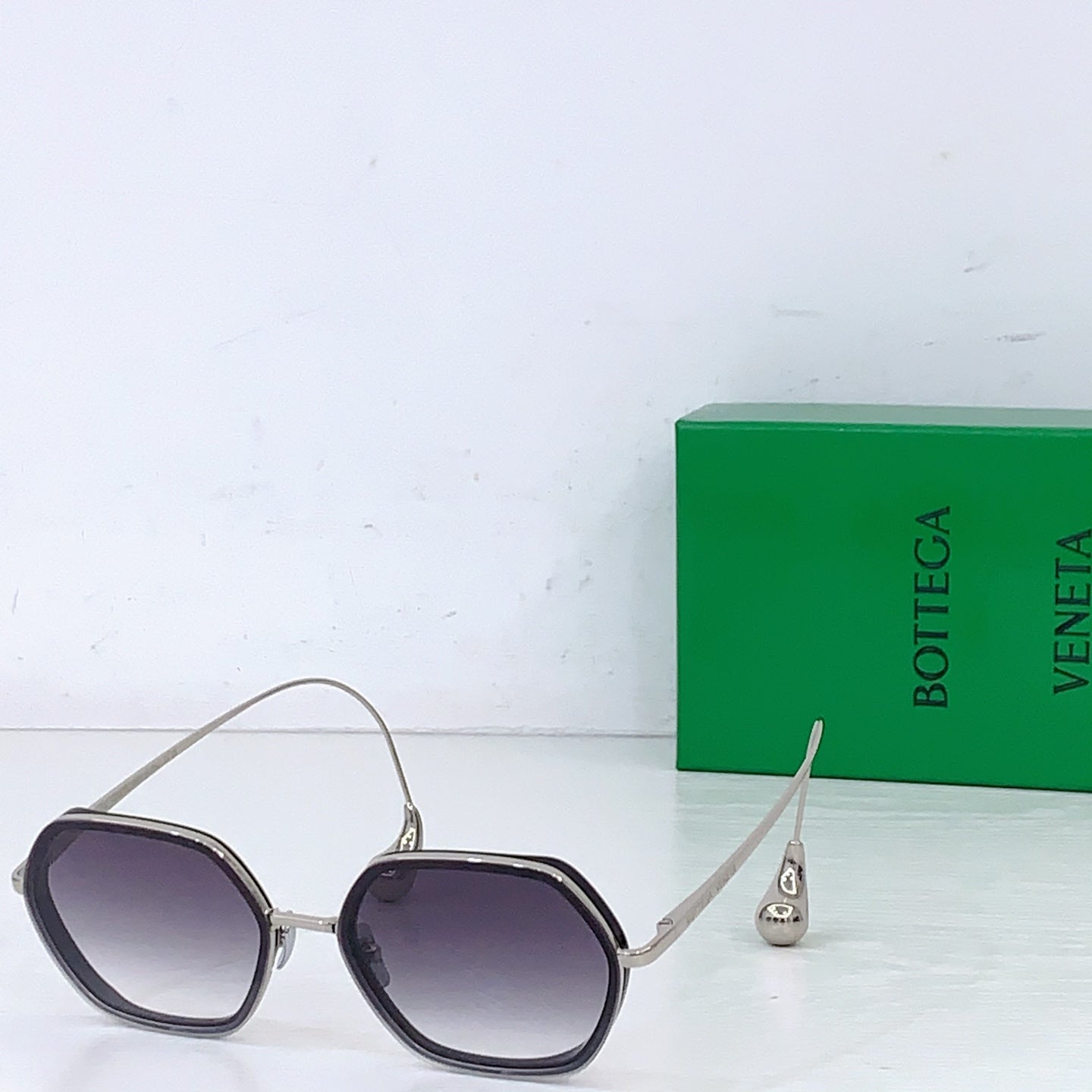 Bottega Veneta sunglasses with dark purple tinted lenses and silver-toned metal frame