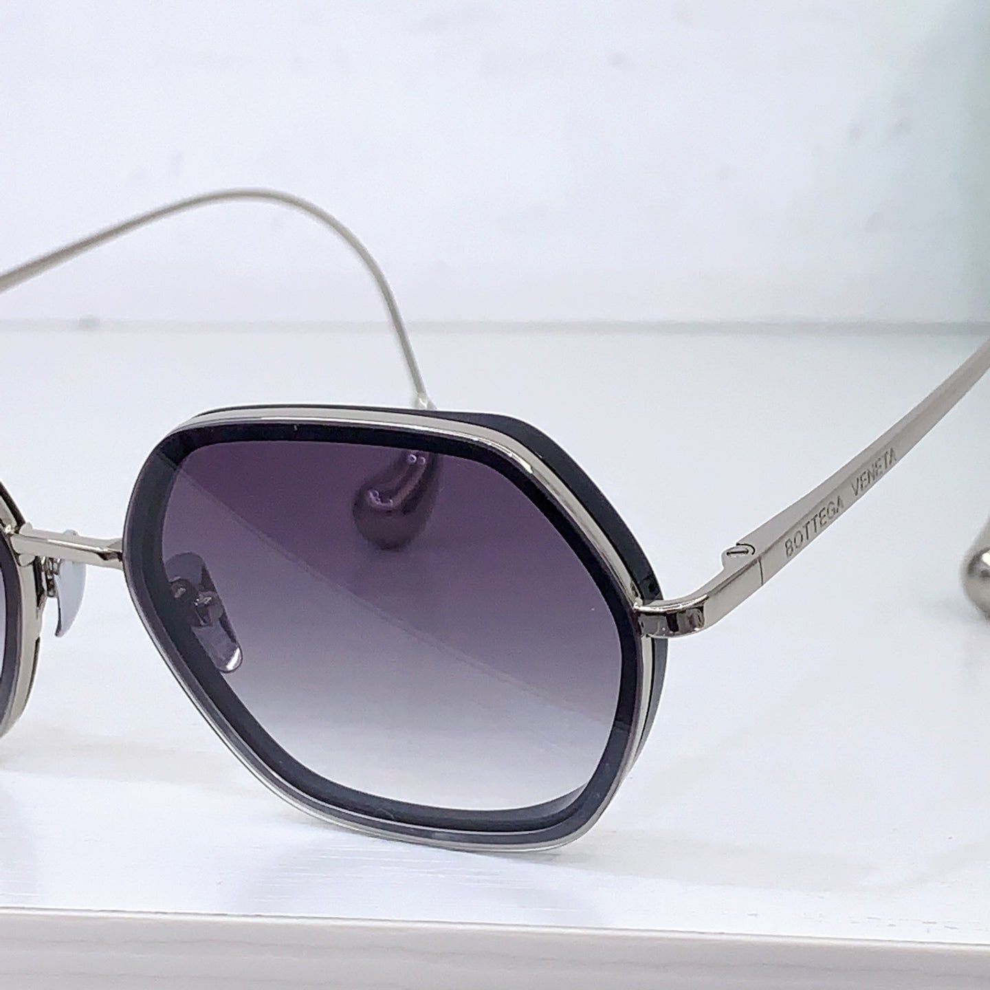 Bottega Veneta sunglasses close-up with dark lenses and silver-toned metal frame