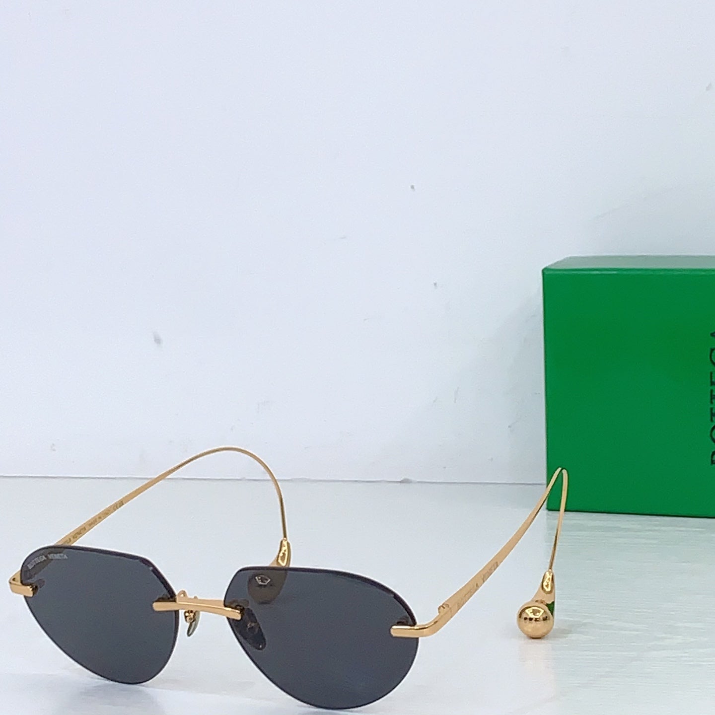 Gold-tone round sunglasses with dark lenses and small logo hinge caps