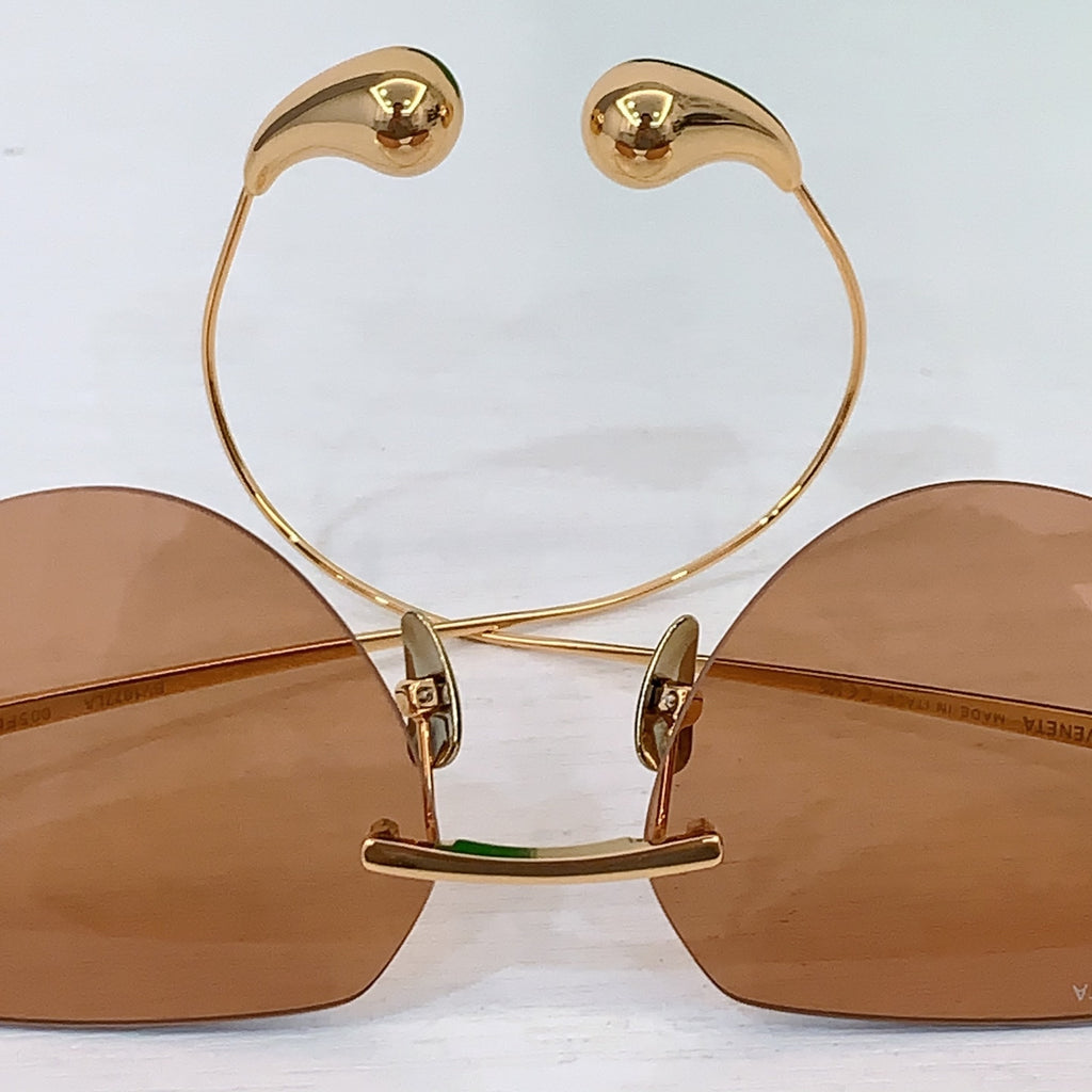 Gold-tone round sunglasses close-up showing bridge and hinge hardware