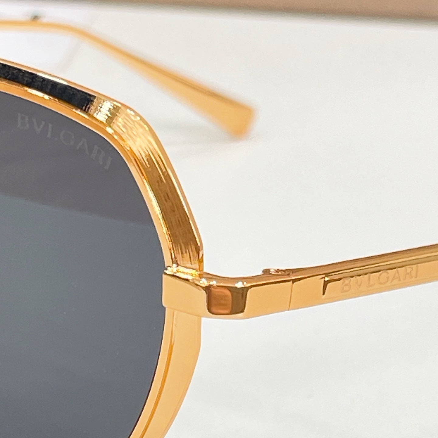 Bvlgari gold sunglasses close-up, round lenses with engraved temple detail