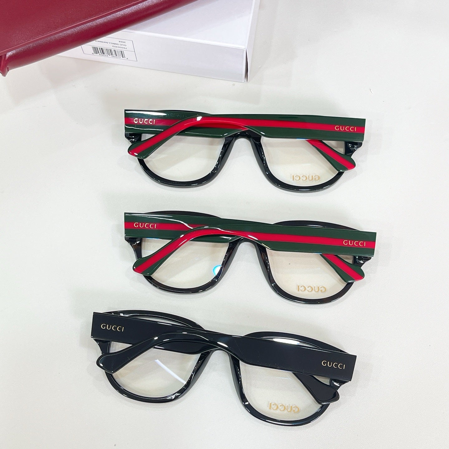 Three black glasses frames with green-and-red striped temples and clear lenses
