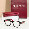 Black acetate glasses with green-and-red striped temples and clear round lenses