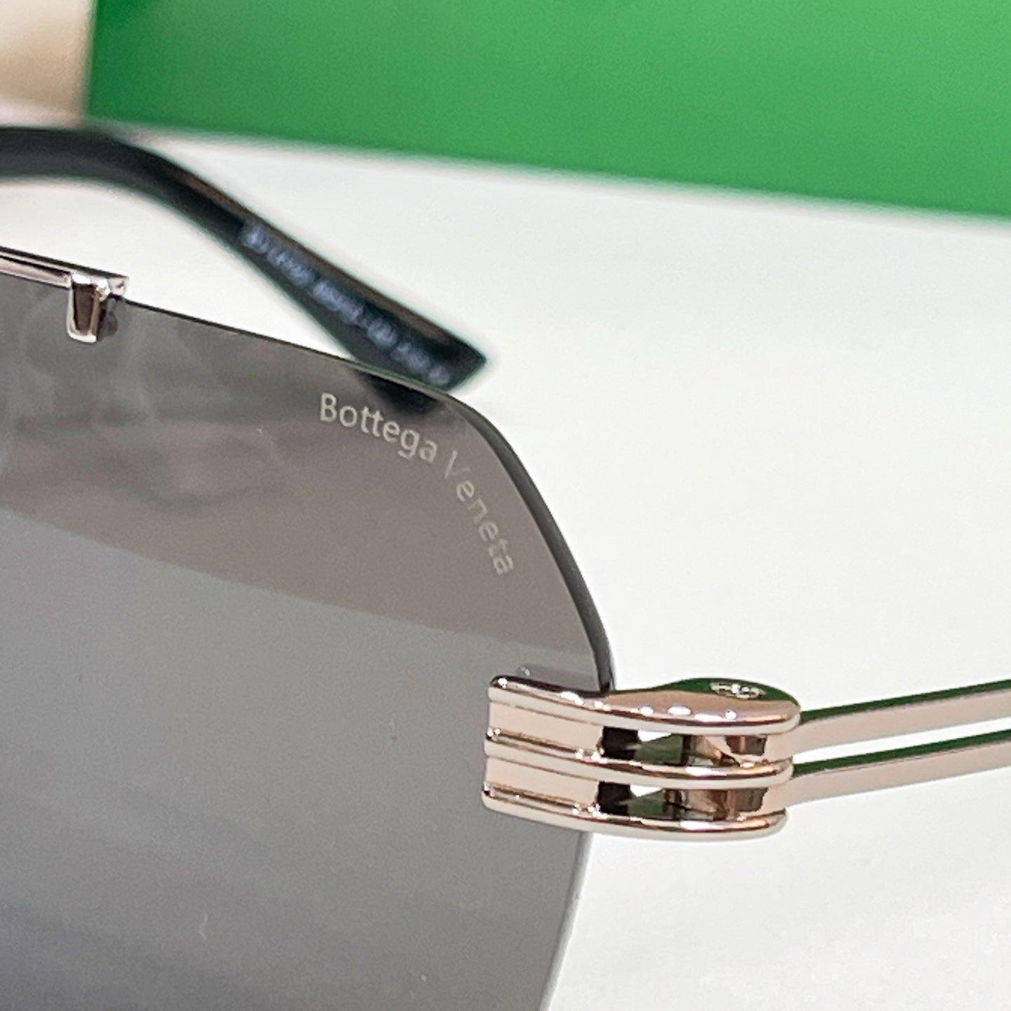 Bottega Veneta sunglasses close-up, metal bridge and temple hinge, engraved temple