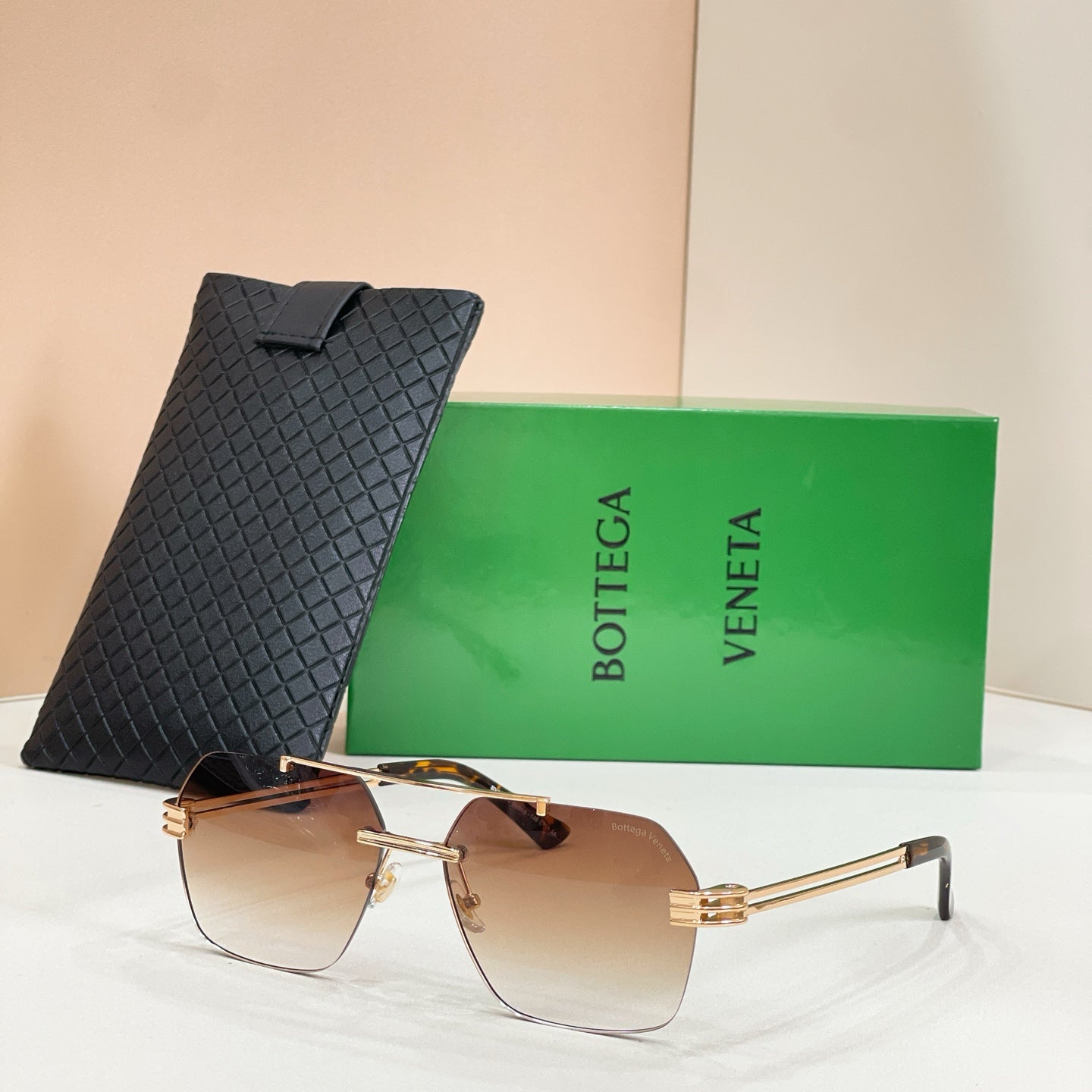 Bottega Veneta aviator sunglasses, warm brown gradient lenses, gold-tone frame, textured black case