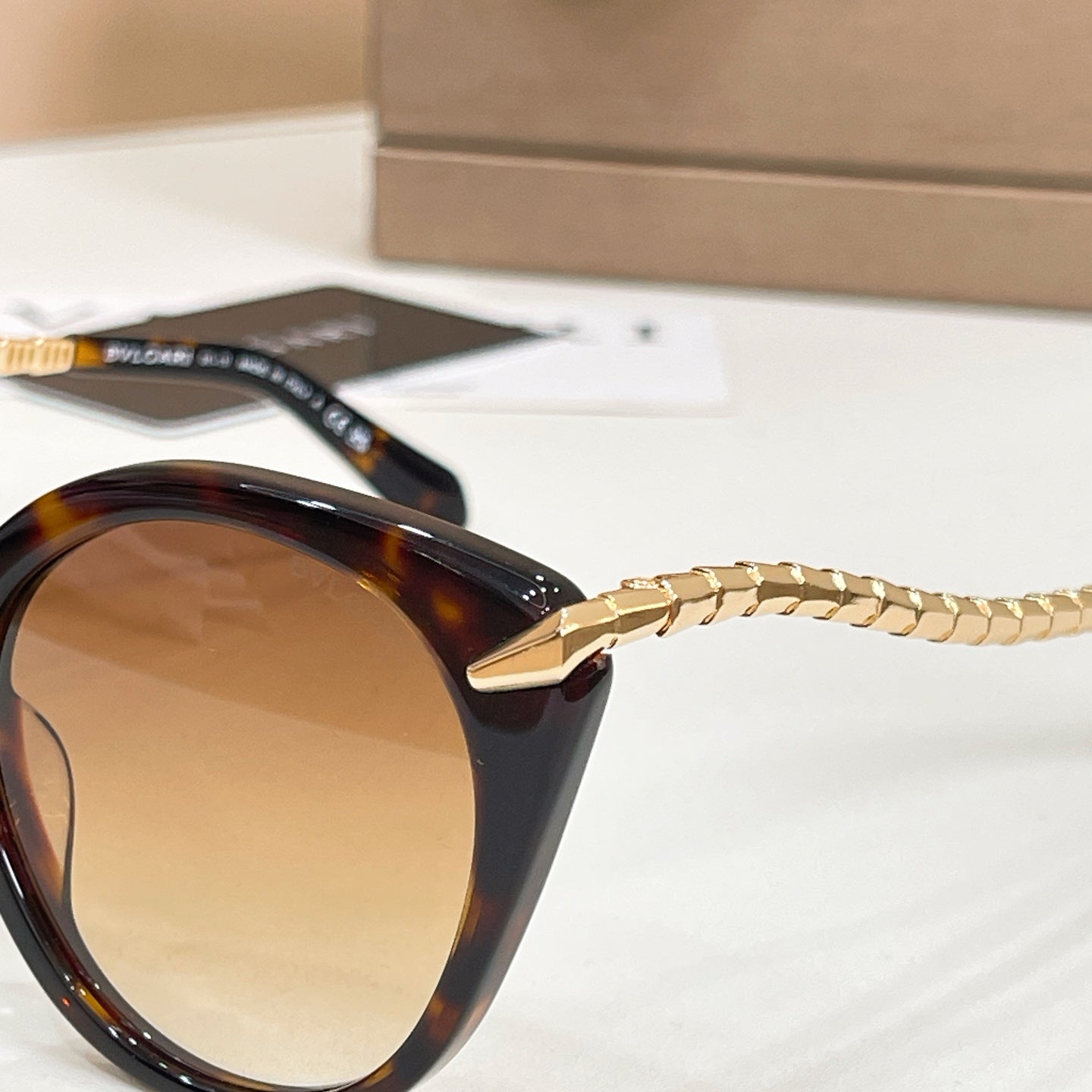 Tortoiseshell cat-eye sunglasses close-up with gold chain arm and tinted lens