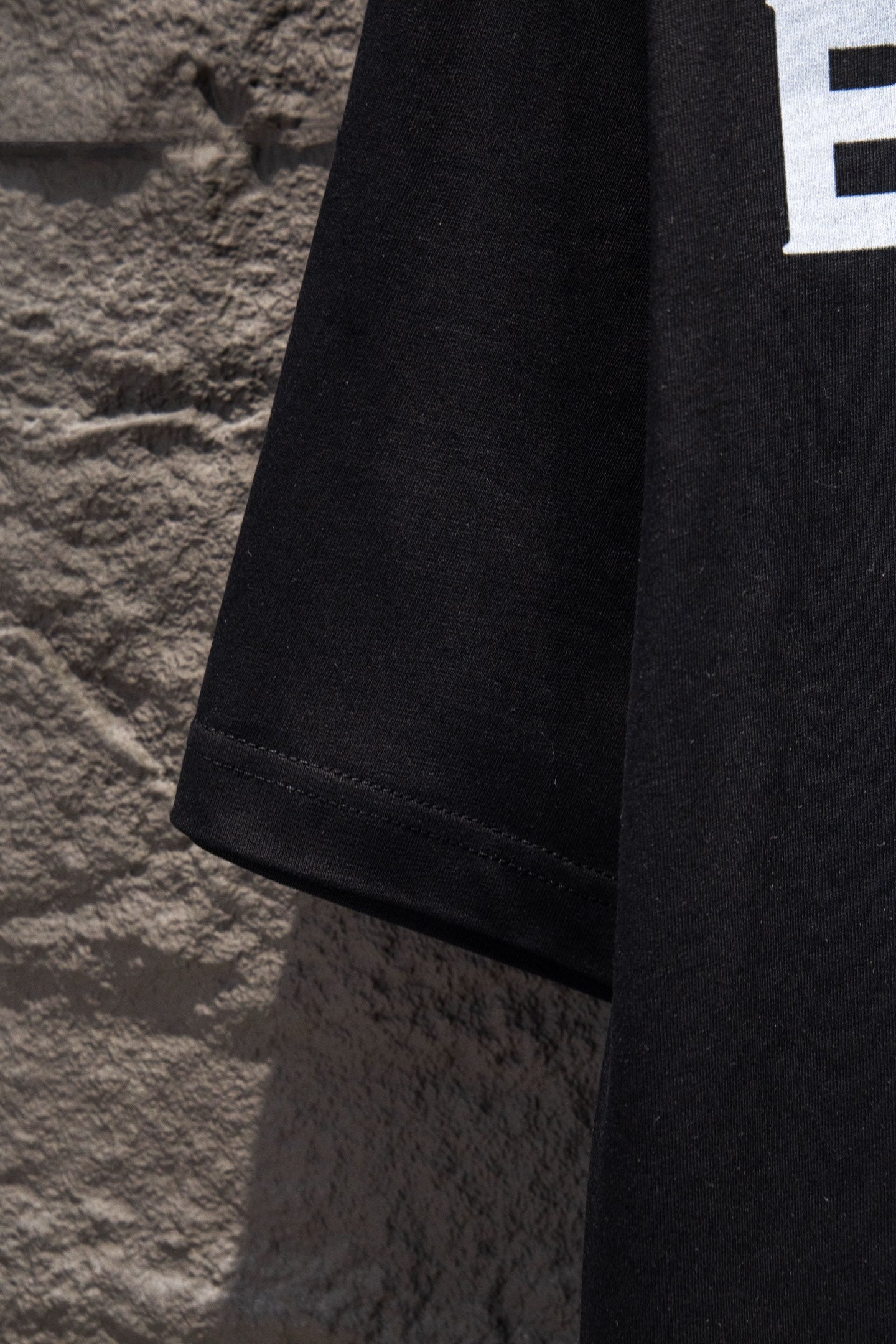 Black T-shirt lower side seam and hem stitching