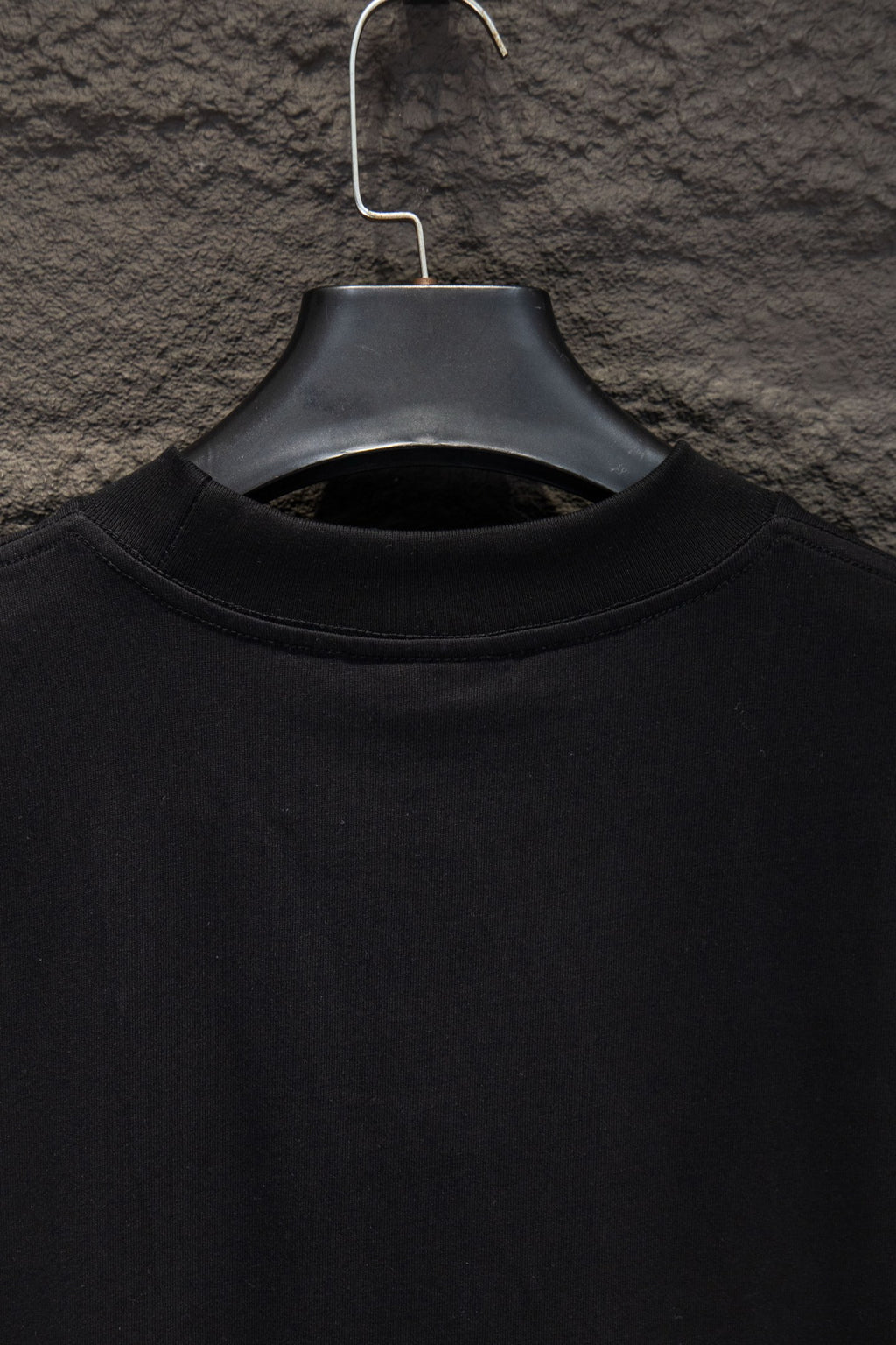 Black crew-neck T-shirt neckline close-up on hanger