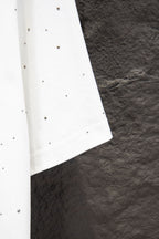 White short-sleeve shirt with stud-like dots and curved side hem