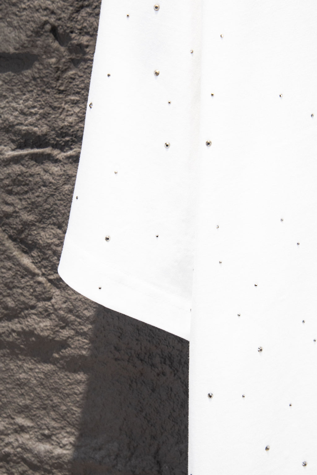 White short-sleeve shirt with scattered stud-like dots and angled side seam