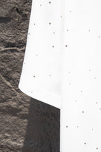 White short-sleeve shirt with scattered stud-like dots and angled side seam