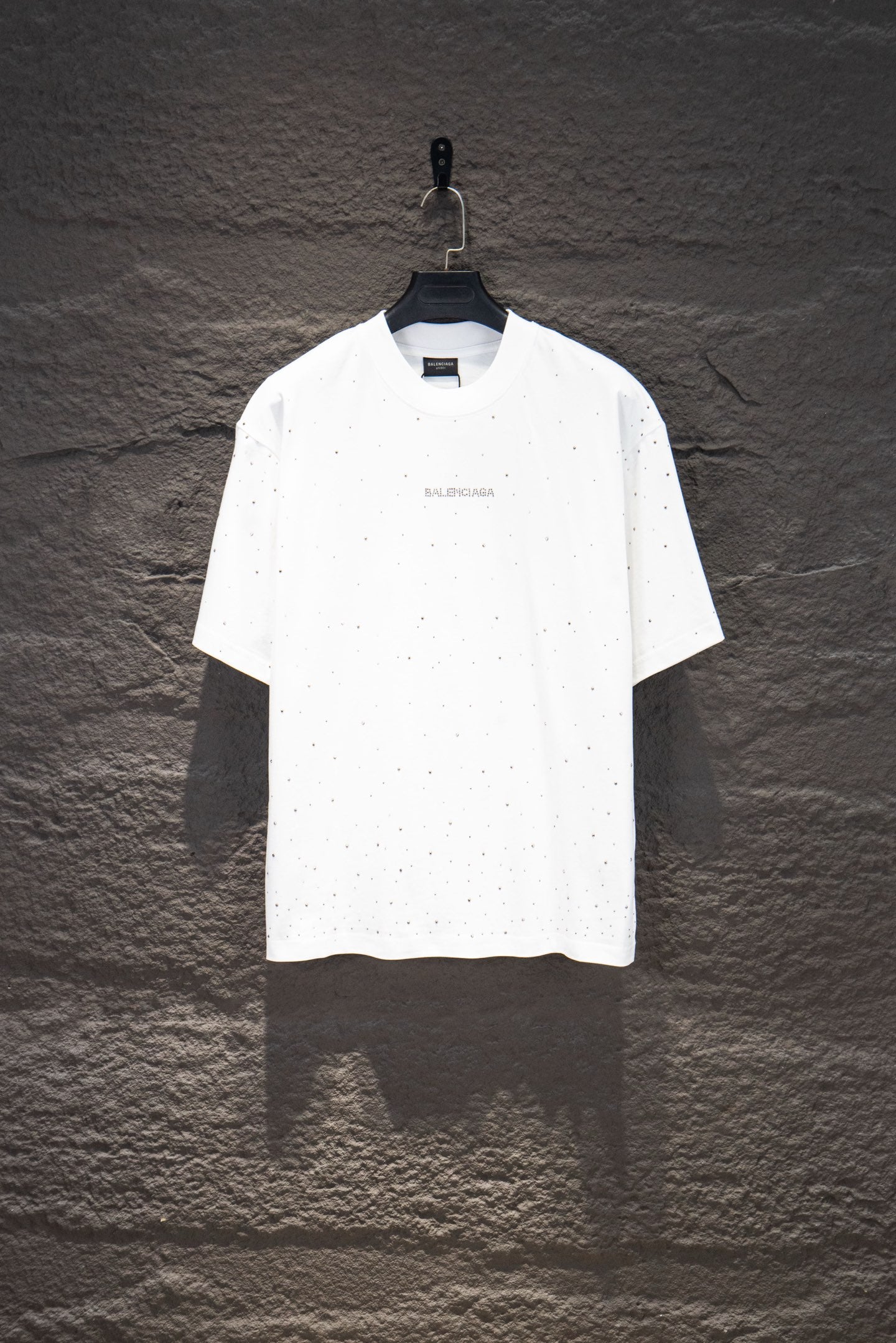 White short-sleeve crewneck shirt with tiny stud-like dots and small chest logo