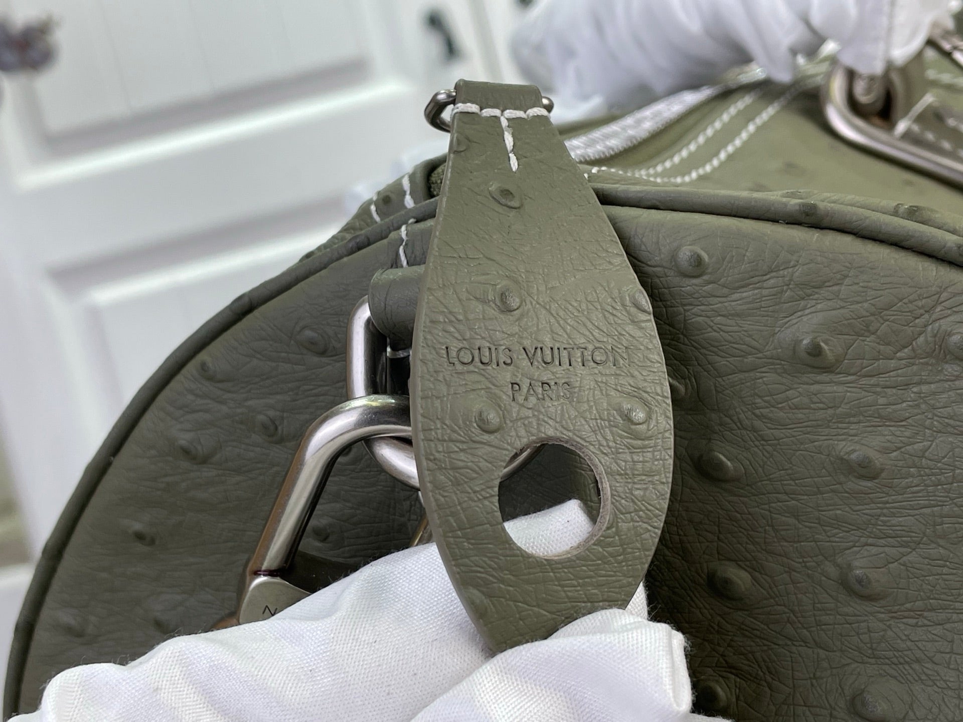 Sage green Louis Vuitton bag handle with embossed logo patch and metal ring