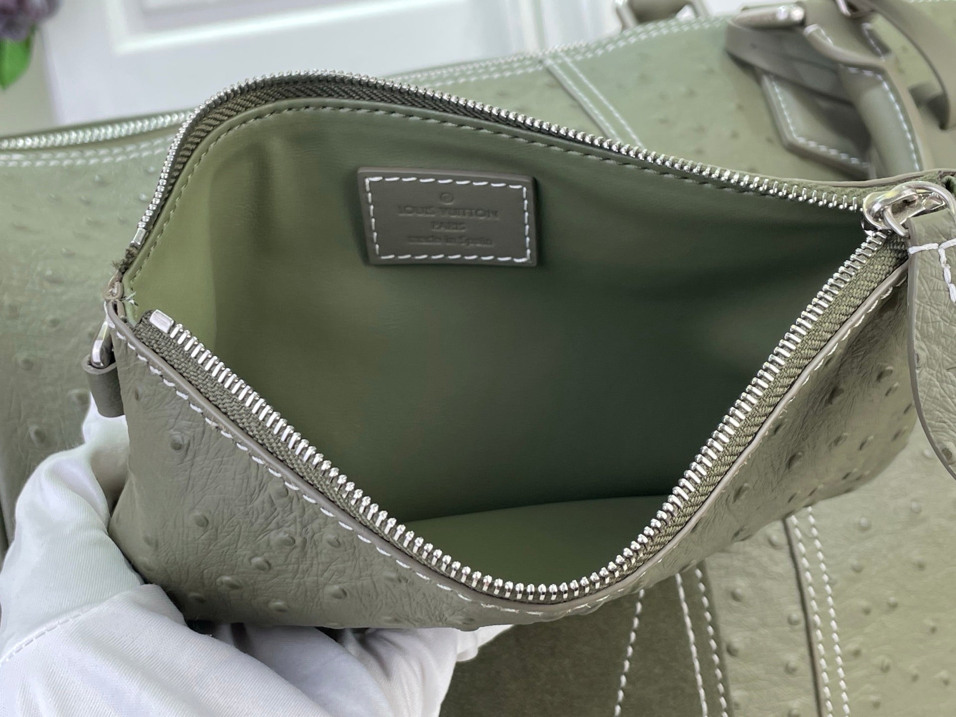 Open sage green Louis Vuitton bag with fabric lining and top zipper