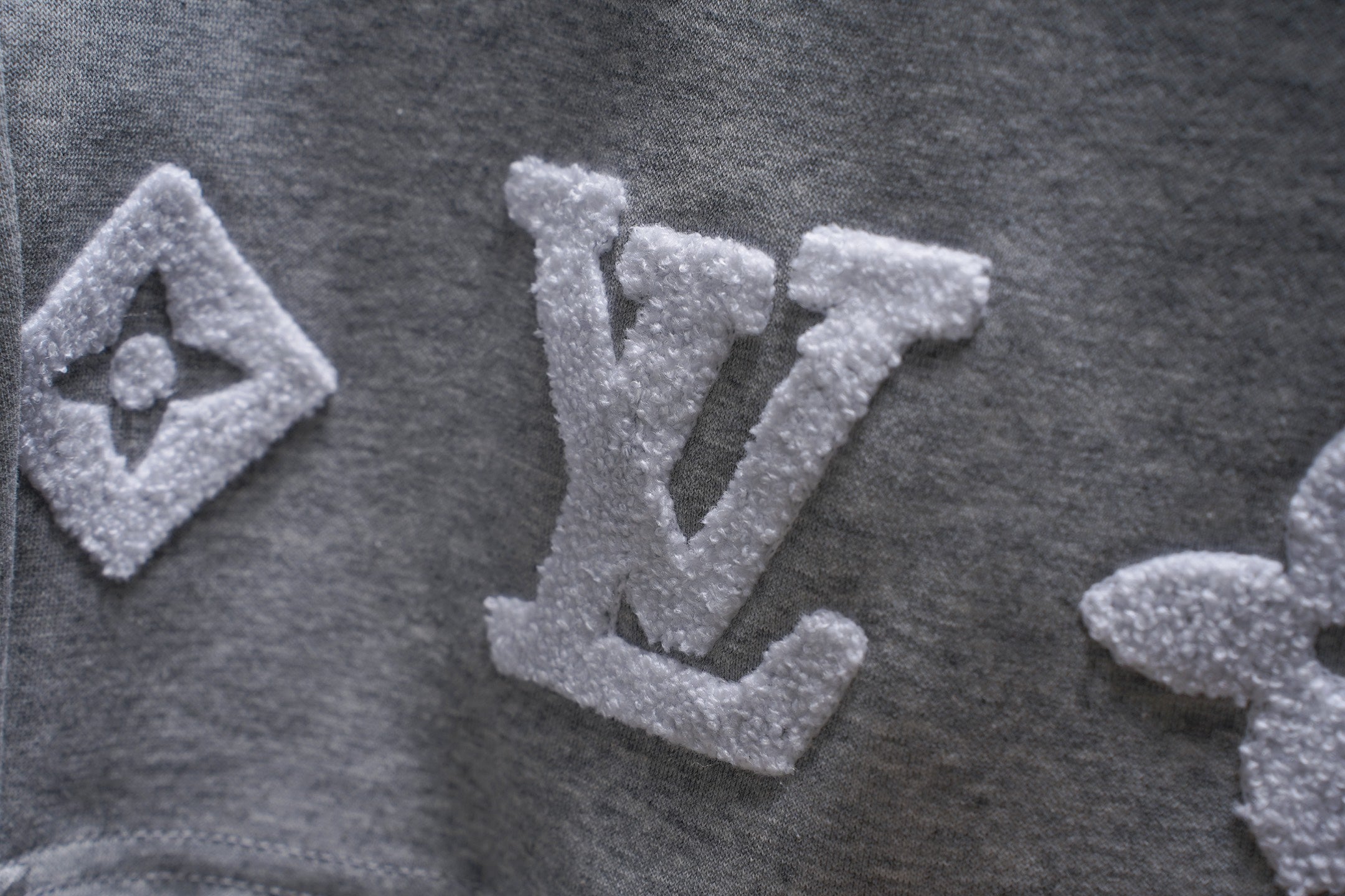 Gray sweat shorts fabric with large embroidered LV monogram motifs