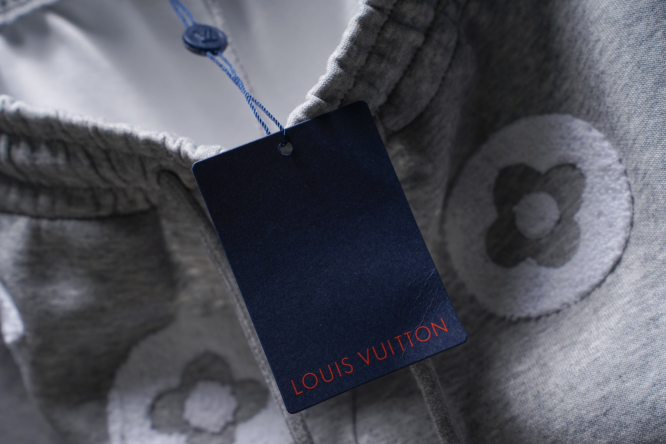 Gray sweat shorts with hanging Louis Vuitton tag and blue drawstring cord