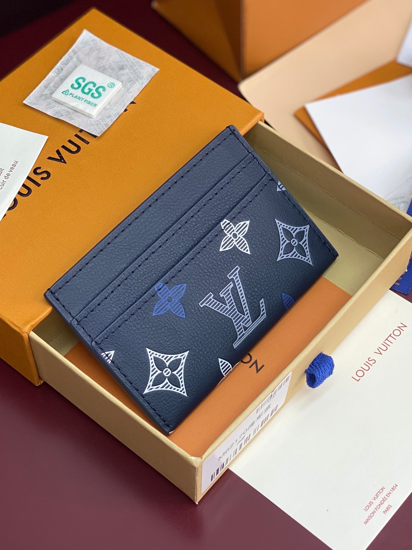 Small navy wallet with repeating white and blue logo pattern, visible card slots.