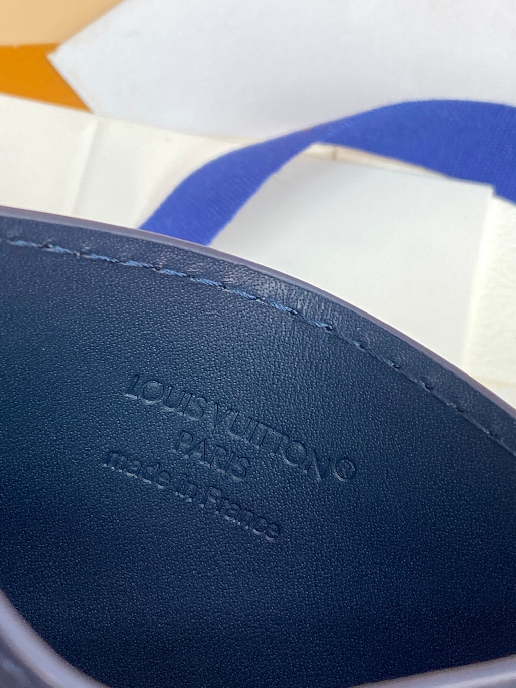 Small navy wallet interior with embossed Louis-style branding and stamped text.