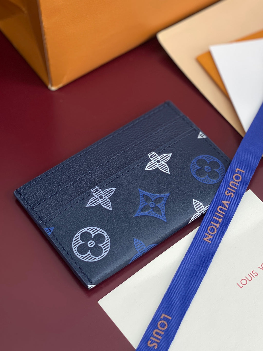 Small navy wallet with embossed-style logo pattern and blue interior label text.
