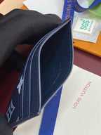 Small navy wallet side view with contrast stitching and printed logo motifs.