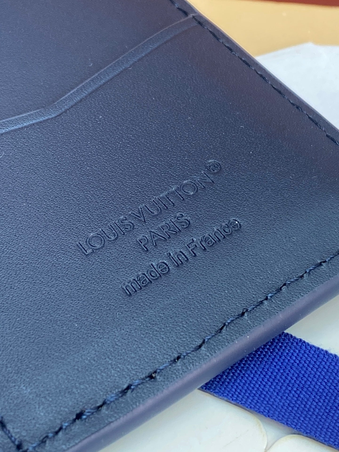 Blue Louis Vuitton small bag with embossed branding and Paris made in France text