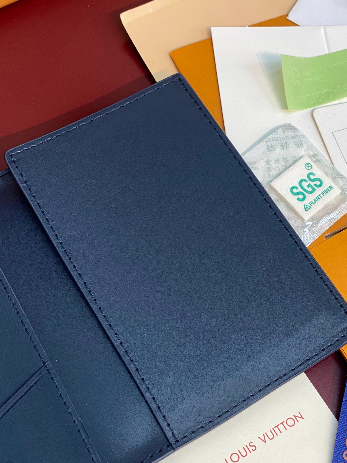 Louis Vuitton card holder close-up in navy blue with smooth front panel and stitching