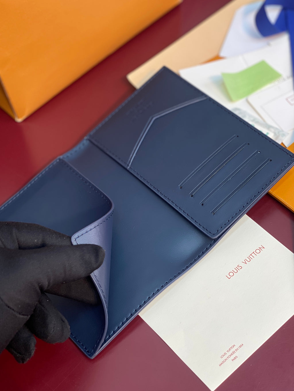 Louis Vuitton small card wallet, dark blue with card-slot panel held by gloved hand