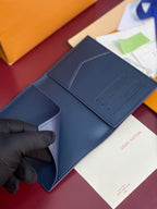 Louis Vuitton card holder open flat, navy blue with four card slots and black-gloved hand