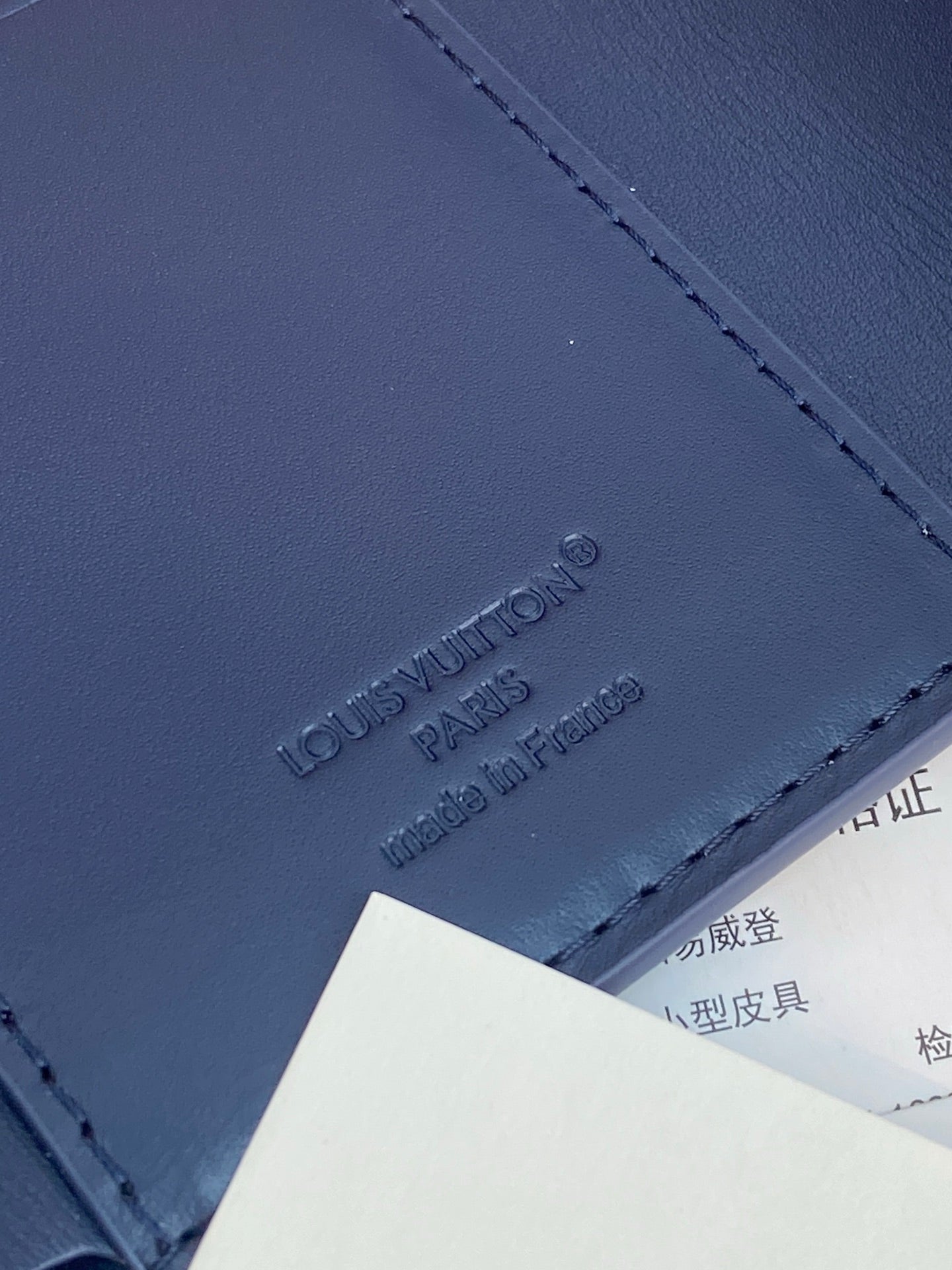 Navy leather wallet close-up with embossed Louis Vuitton Paris logo