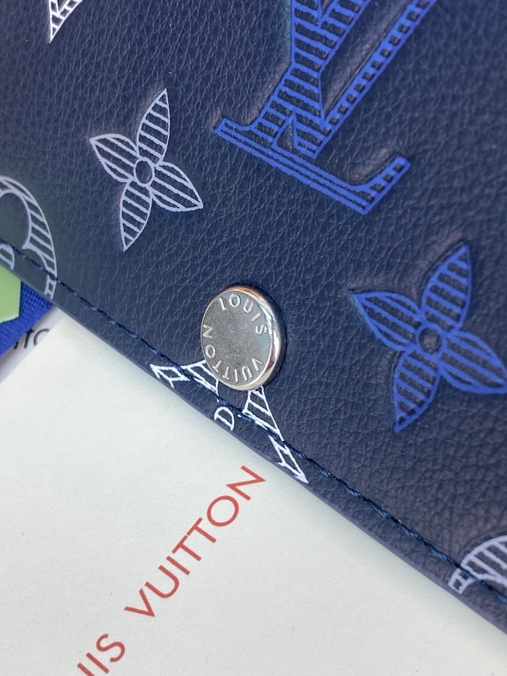 Navy patterned wallet corner with silver snap button and visible stitching