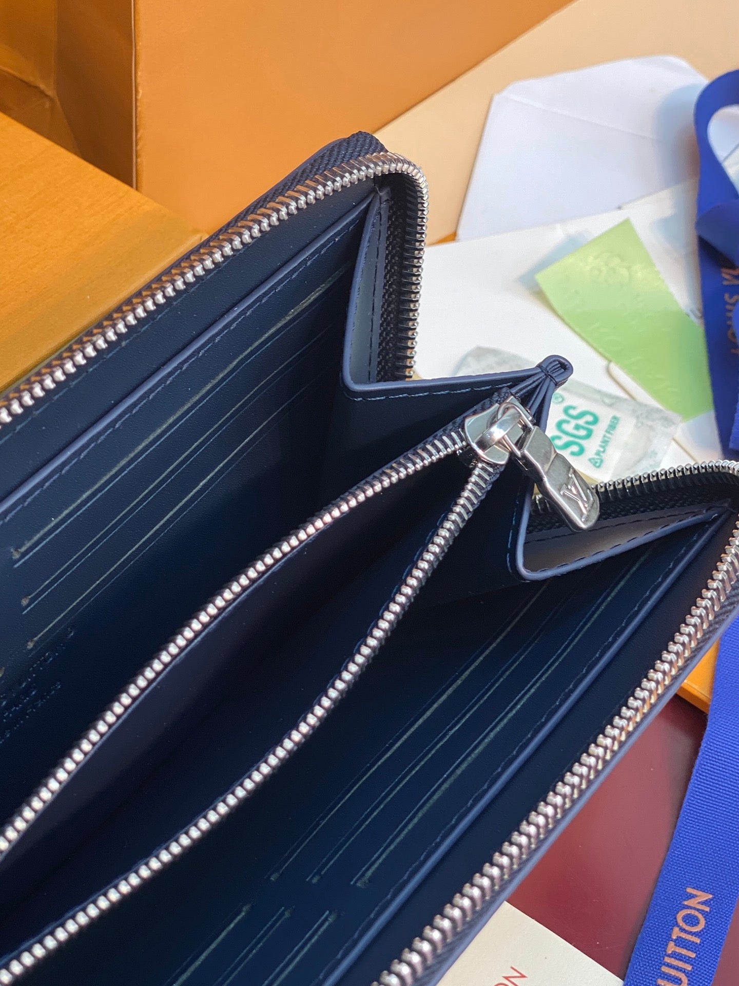 Louis Vuitton zip wallet interior in dark blue with card slots and silver zippers.
